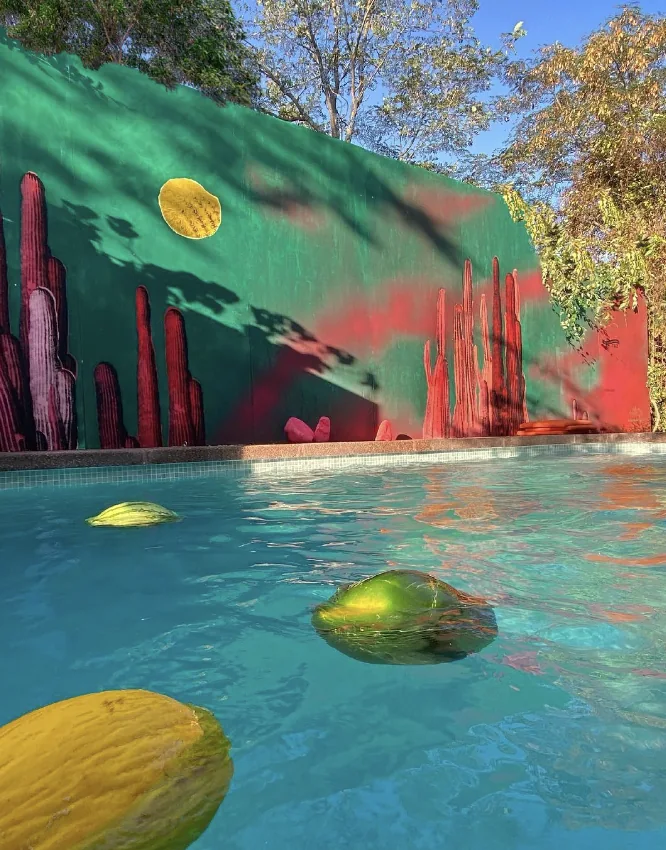 Mural verde y rojo junto a una piscina, con formas de cactus
